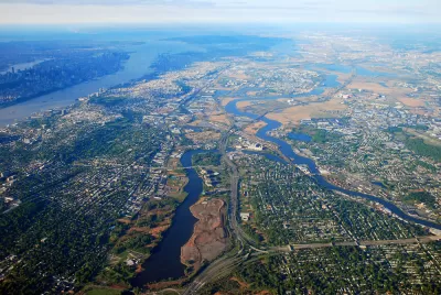 An aerial view of New Jersey suburbs, with Manhattan and New York City in the distant background.