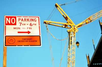 A sign reads “No Parking” for temporary construction, with a construction crane in the background.