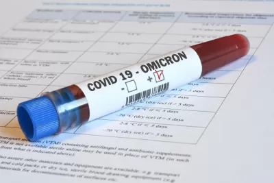 A vial of blood marked "Omicron" sits on top of paperwork indicating relevance to Covid-19.