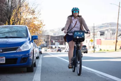 Woman wearing helmet riding POGOH bike share bike in bike lane in Pittsburgh, PA.
