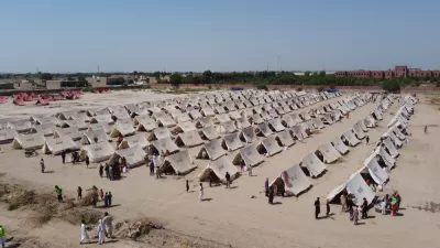 A humanitarian facility, with rows of tents, is set up in a dusty field in Pakistan.
