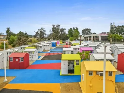Multicolored tiny homes for temporary shelter in complex adjacent to freeway overpass in Los Angeles, California.