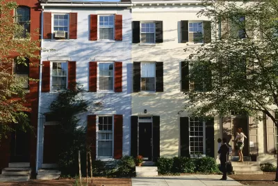 A family exits from a rowhouse. Picture is identifiably from the 1980s based on the clothing fashion of the family.