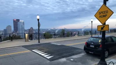 Wide speed hump on Pittsburgh bridge with yellow Speed Hump sign on sidewalk.