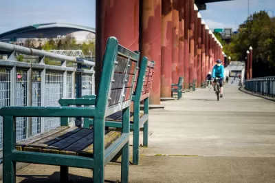 A single bike rider wearing a mask rides along a waterfront in Portland, Oregon.