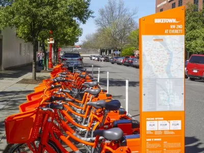 Numerous orange Portland Biketown bikes are parked at a facility in Northwest Oregon.