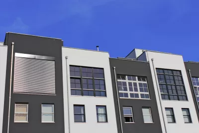The top floors of a row of pre-fab apartments or condos are shown against a blue sky.