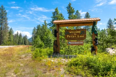 A wooden sign on the side of a road welcomes visitors to Priest Lake in Idaho.
