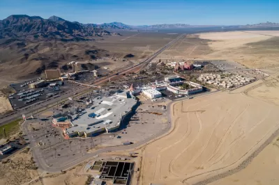 A aerical view of primm, Nevada, where I-15 bisects large casinos and parking lots on a sunny day.
