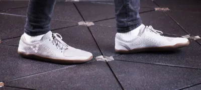 Close-up of white sneakers walking on solar-powered sidewalk panels.