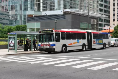 A bus stop in Philadelphia, where people wait under a glass shelter for a bus as it arrives.