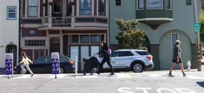 People walking on San Francisco street with 'Slow Streets' signs.