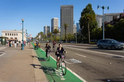 A group of cyclists rides on a green painted bike line on the Embarcadero in Sa Francisco.