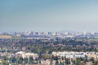 A view out over the city of San Jose, with downtown highrises in the background distance and smoggy air hanging overhead.