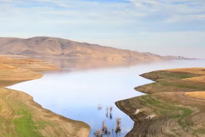 A barren landscape surrounds a reservoir well below its capacity.