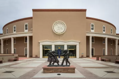 The New Mexico State Capitol building, with a statue of small children playing in the foreground.
