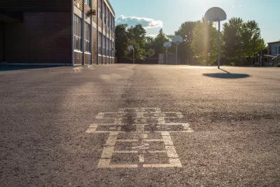 Hopscotch squares on concrete schoolyard with basketball hoop in background