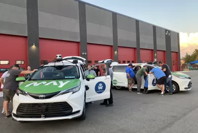 People examining parked goMARTI vans at launch event