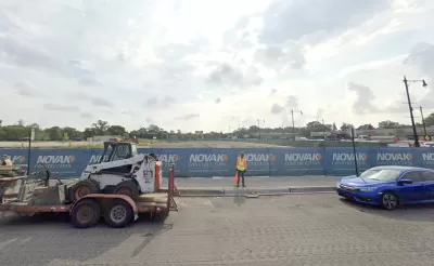 Google Street View of empty construction site with blue construction fence