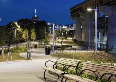 Benches along lit paved bike trail adjacent to freeway overpass in Albany, New York