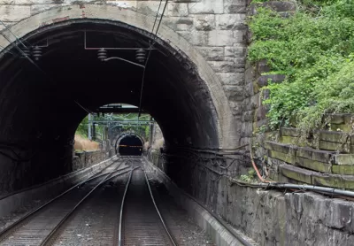 View into gray stone train tunnel with visible opening on other side