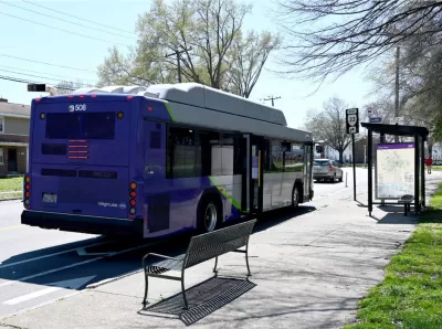 Purple GRTC bus stopped at a bus station with bench and shelter in Richmond, Virginia.