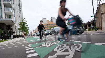 Cyclists riding on green painted bike lane protected by flexible post delineators in Chicago, Illinois.