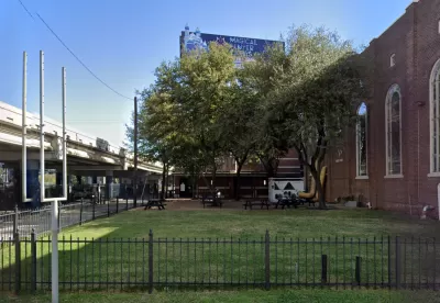 Google street view of grassy lot next to brick church with elevated freeway on other side in Houston, Texas.