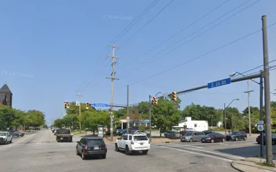 Google street view of wide street in Cleveland, Ohio with blue 55th Street sign and red brick three-story building visible in right corner.