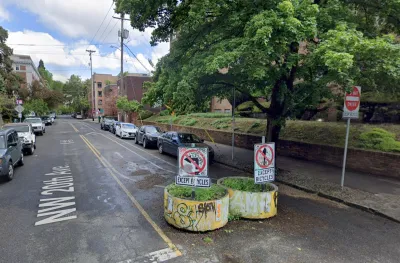 Two yellow concrete planters with graffiti on one-way street in Portland, Oregon designed to divert car traffic while allowing cyclists and pedestrians through.