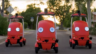 Three red DoorDash delivery robots facing camera on suburban street.