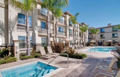 Hotel pool and hot tub at Spanish-style hotel in Carlsbad, California on sunny day.