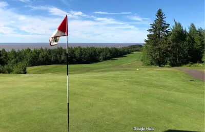 Golf course green with red flag in foreground against a bright blue sky in Duluth, Minnesota.