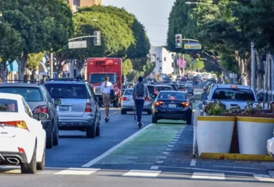 Car blocking bike lane in Santa Monica, CA with e-scooter rider behind it.