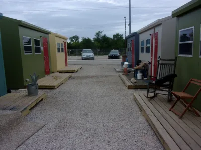 Row of green and yellow tiny homes in Esperanza Community shelter in Austin, Texas.