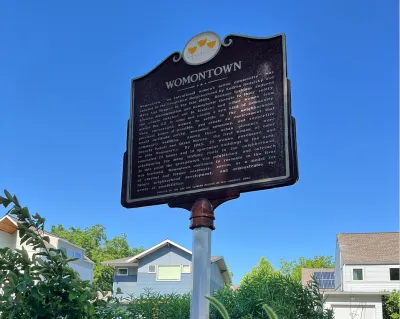 Womontown historical plaque next to houses in Kansas City, Missouri.