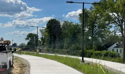 Workers building paved two-sided bike and walking trail next to single-family homes in Detroit, Michigan.