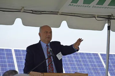 MIRA President Tom Kirk gestures at the opening ceremony of the solar array at the Hartford Landfill. There are rows of solar panels behind him.