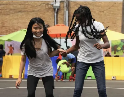 Two Black children roller skate.
