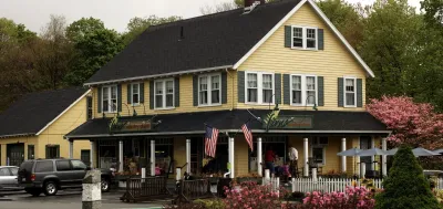 A yellow, two-story building named Ferns with two American flags.