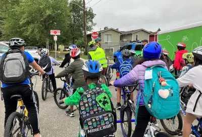Group of children with backpacks and bike helmets going to school.