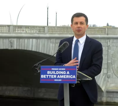 U.S> Department of Transportation Secretary Pete Buttigieg delivers a speech in front of a bridge in Washington, D.C. The podium where he stands has a sign that reads: "Building a Better America."