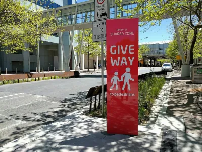 Red sign with "Give Way" and pedestrian icons on 'shared street' with 15kph speed limit in Canberra, Australia.