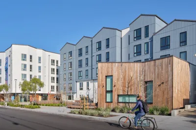 Rendering of Shirley Chisholm Village four-story housing development with person biking in front.