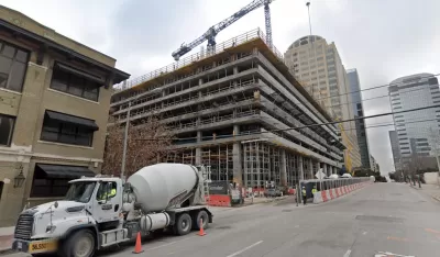 Construction on a high-rise, with cement trucks and tall cranes, is visible on an Austin Street.