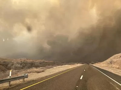 Two-lane asphalt road with smoke filling the sky in Texas Panhandle.
