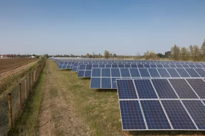 Solar panels are lined up on agricultural land. 