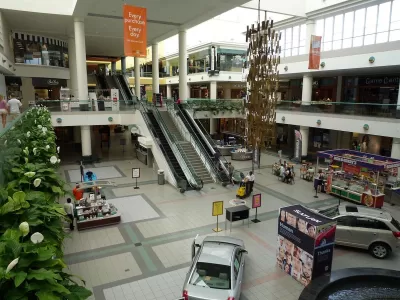 View form second story inside Southdale Mall in Edina, Minnesota with escalators and model cars parked on downstairs floor.
