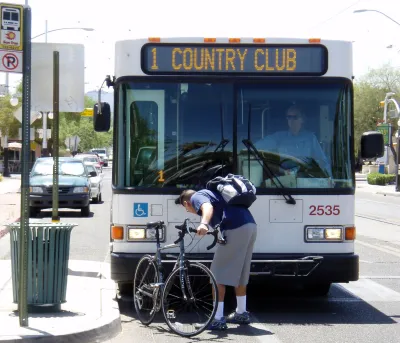 Man loading or unloading bike from rack on front of public transit bus in Tucson, Arizona.