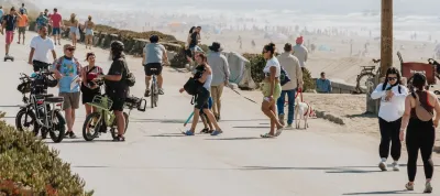Crowds of people walking and biking along waterfront in Sunset Dunes Park in San Francisco, California on a sunny day.